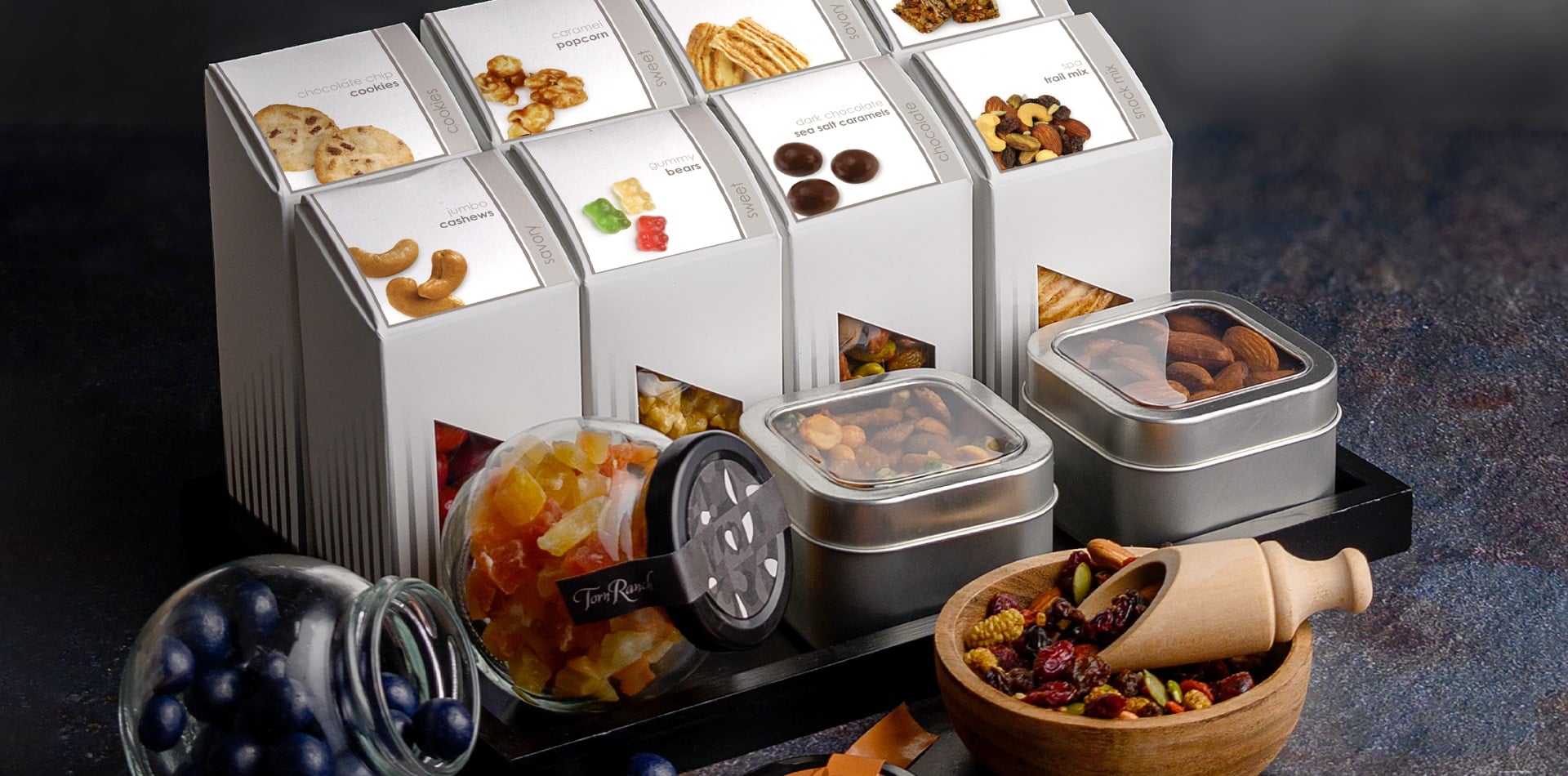 Modern hotel minibar stocked with Torn Ranch gourmet truffles, nuts, and popcorn presented as luxury in-room amenities.